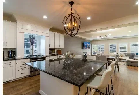 Spherical chandelier above a kitchen island with recessed ceiling lights