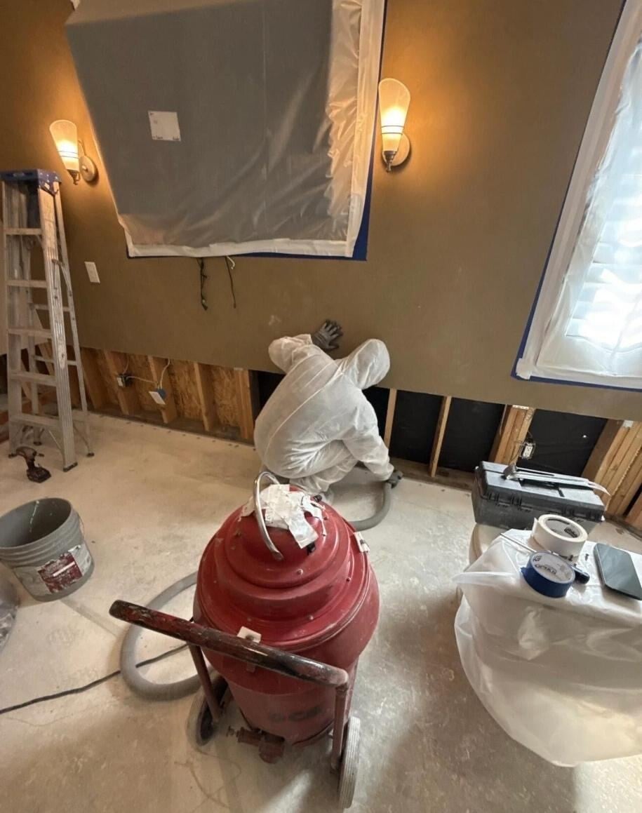 VIP technician in a protective suit removing damaged drywall