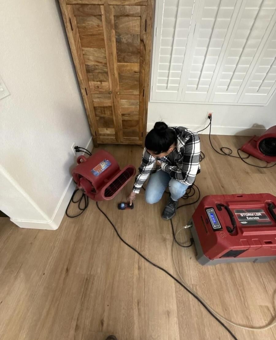 Technician checking moisture levels beside drying equipment
