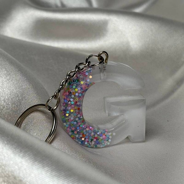 Resinschlüsselanhänger Buchstabe G mit weißem Glitzerhintergrund und buntem Glitzer im Vordergrund