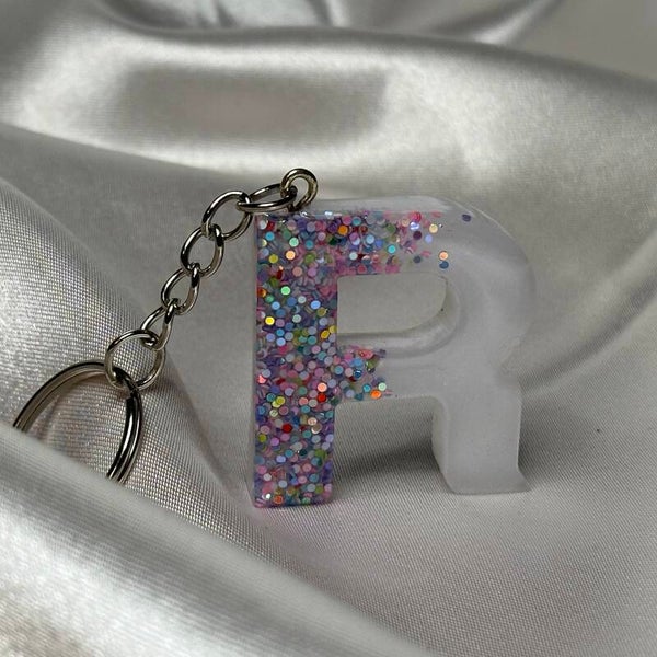 Resinschlüsselanhänger Buchstabe R mit weißem Glitzerhintergrund und buntem Glitzer im Vordergrund