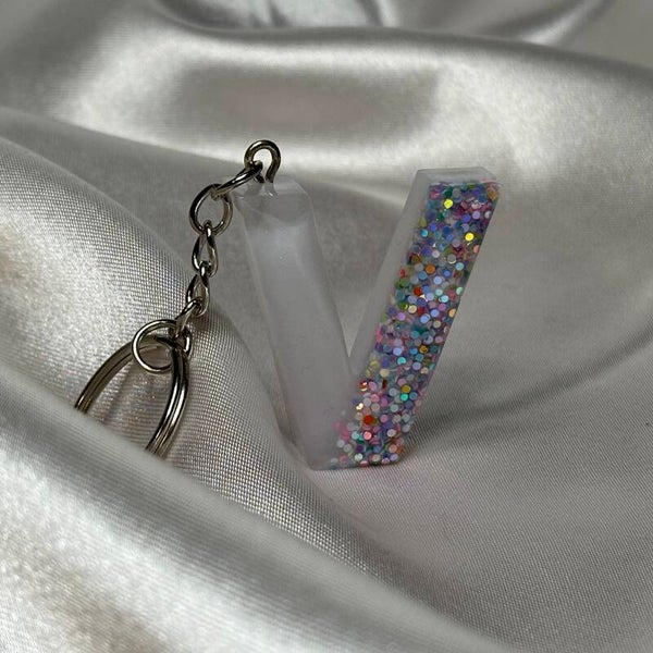 Resinschlüsselanhänger Buchstabe V mit weißem Glitzerhintergrund und buntem Glitzer im Vordergrund