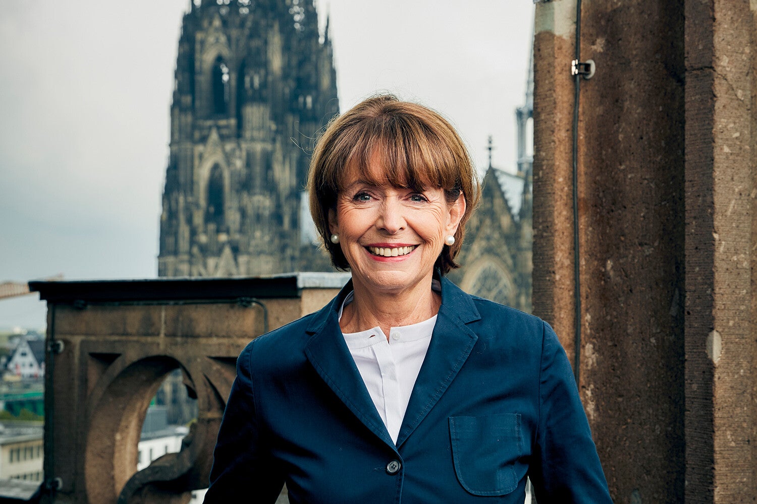 Ein Foto einer strahlenden Oberbürgermeisterin Hennriette Reker vor der Kulisse des Kölner Doms