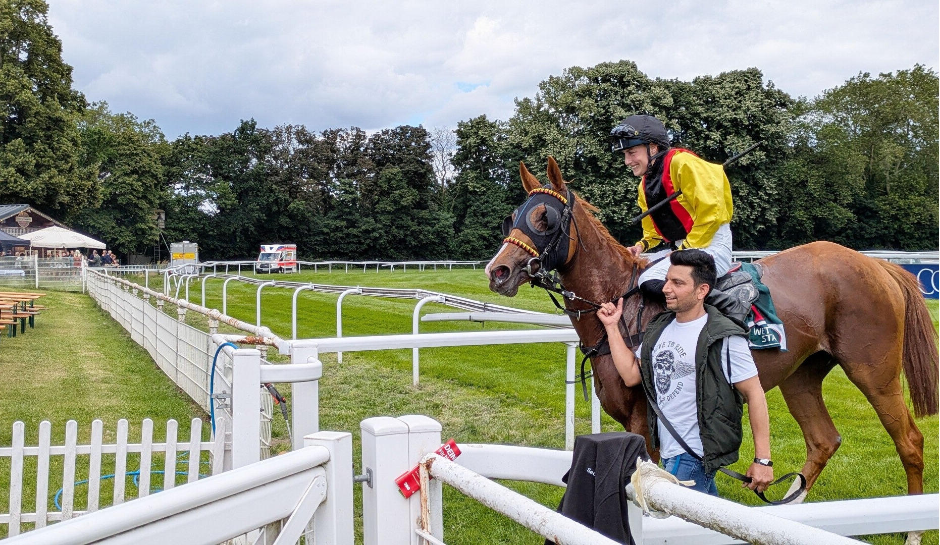 Ein stolzer Jockey mit bunter Jacke bei der Pferderennbahn in Köln