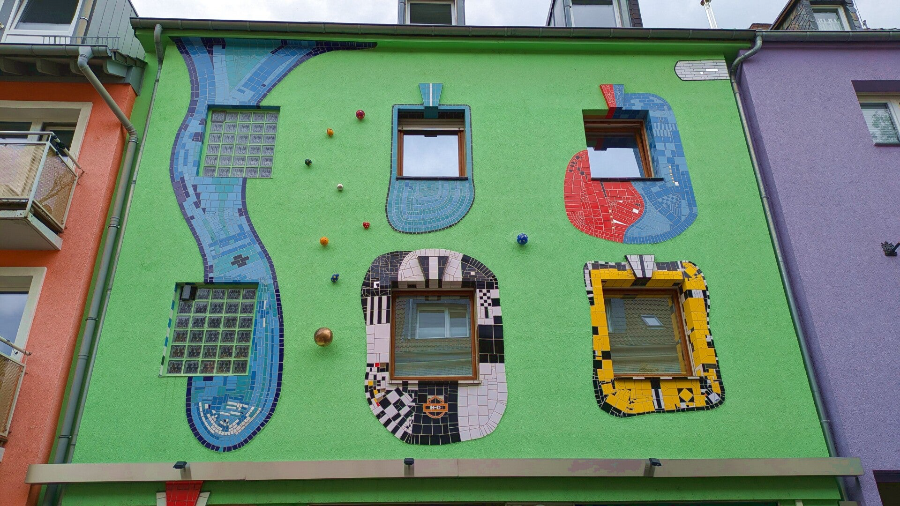 Hausfassade mit künstlerischen Mosaiken rund um die Fenster – Kalk