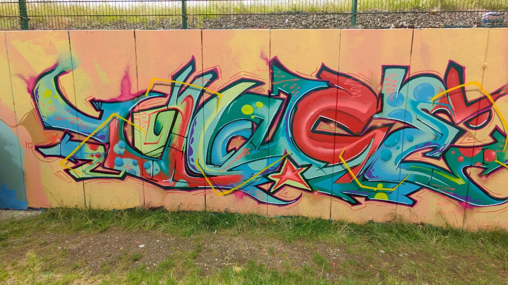 Farbiger Graffiti-Schriftzug auf einer Mauer – StreetArt Kalk