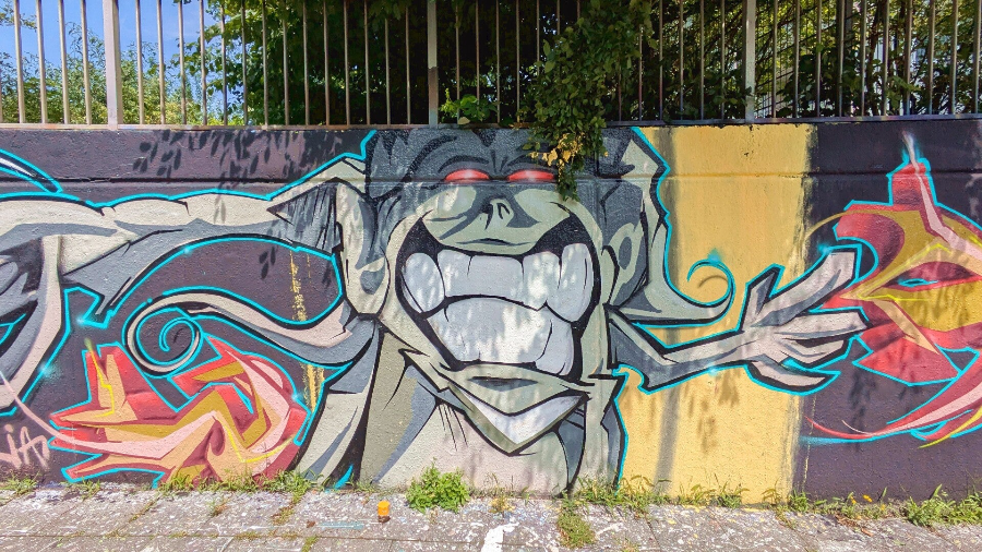 Grinsende, bunte Fantasiefigur als StreetArt – Köln-Nippes