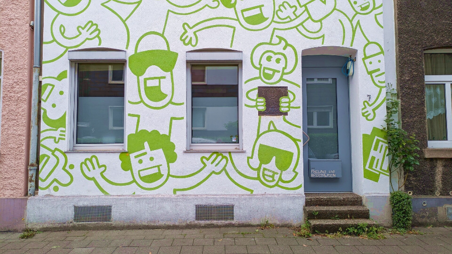 Bunte Comicfiguren auf einer kompletten Hausfassade – Kalk