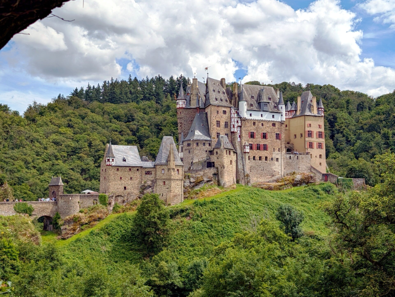 Blick auf die majestätische Burg Eltz, die auf einer Anhöhe thront und von dichten Wäldern umgeben ist