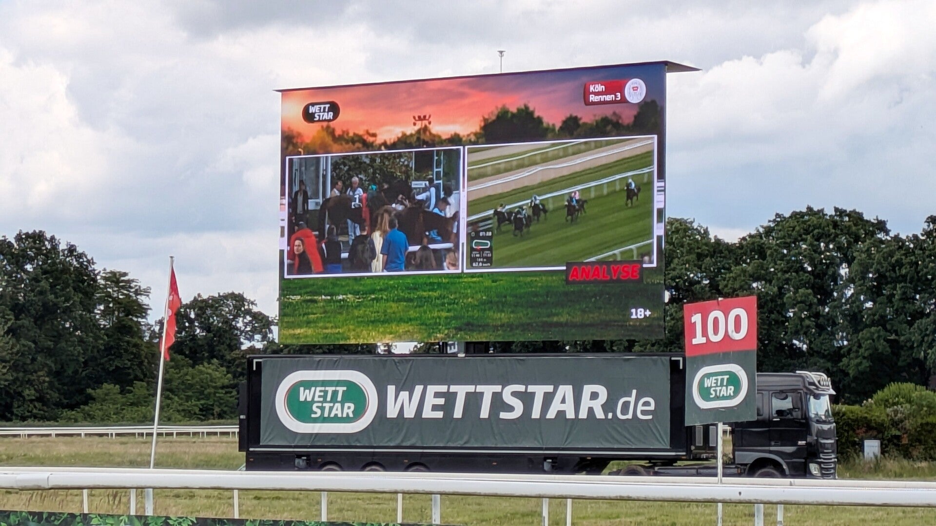 Blick auf eine riesige Videoleinwand neben dem Zieleinlauf bei der Pferderennbahn in Köln