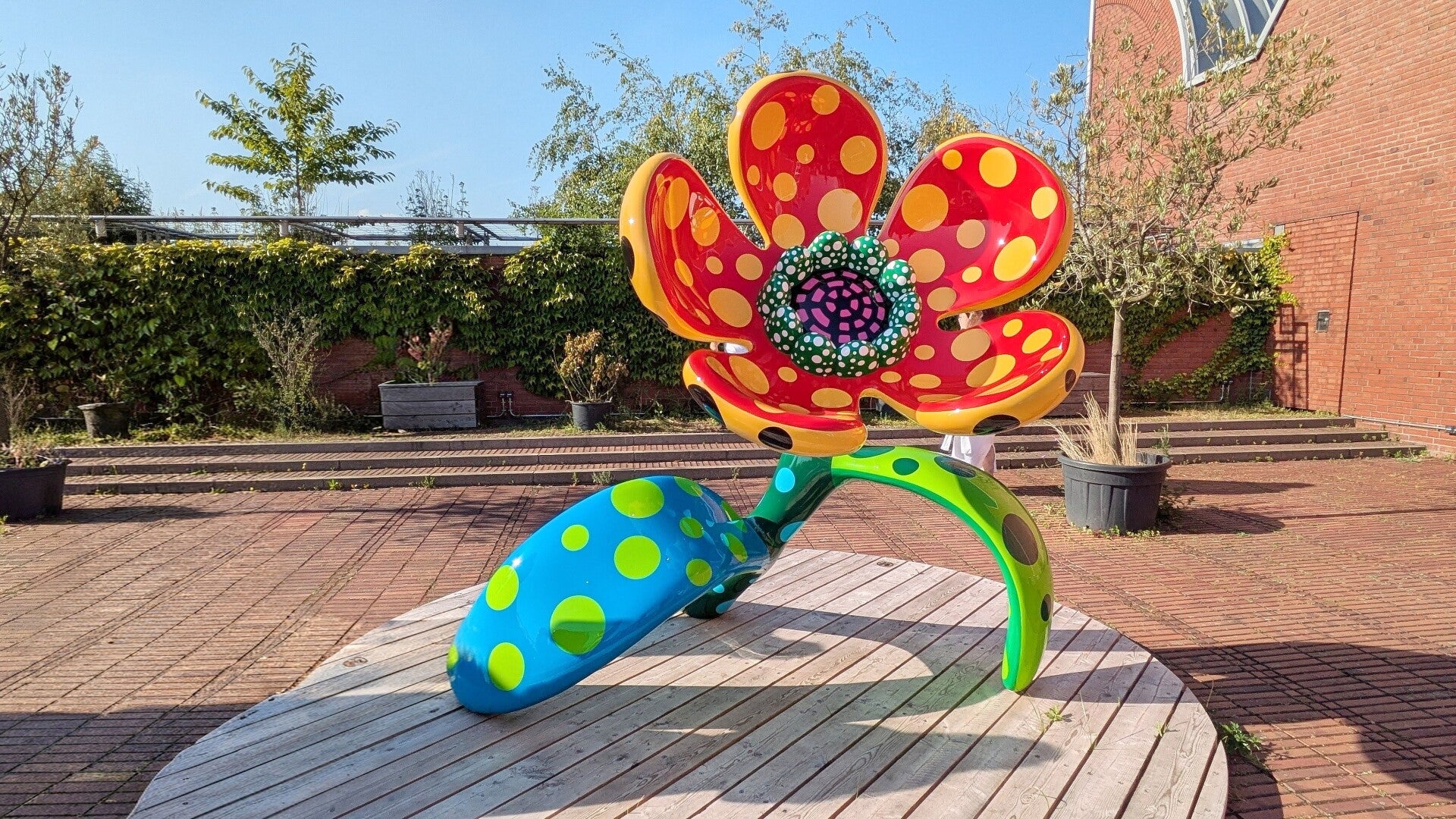 Eine bunte grosse Blume aus Pappmachee auf dem Dach  bei der Ausstellung  Yayoi Kusama im Museum Ludwig in Köln