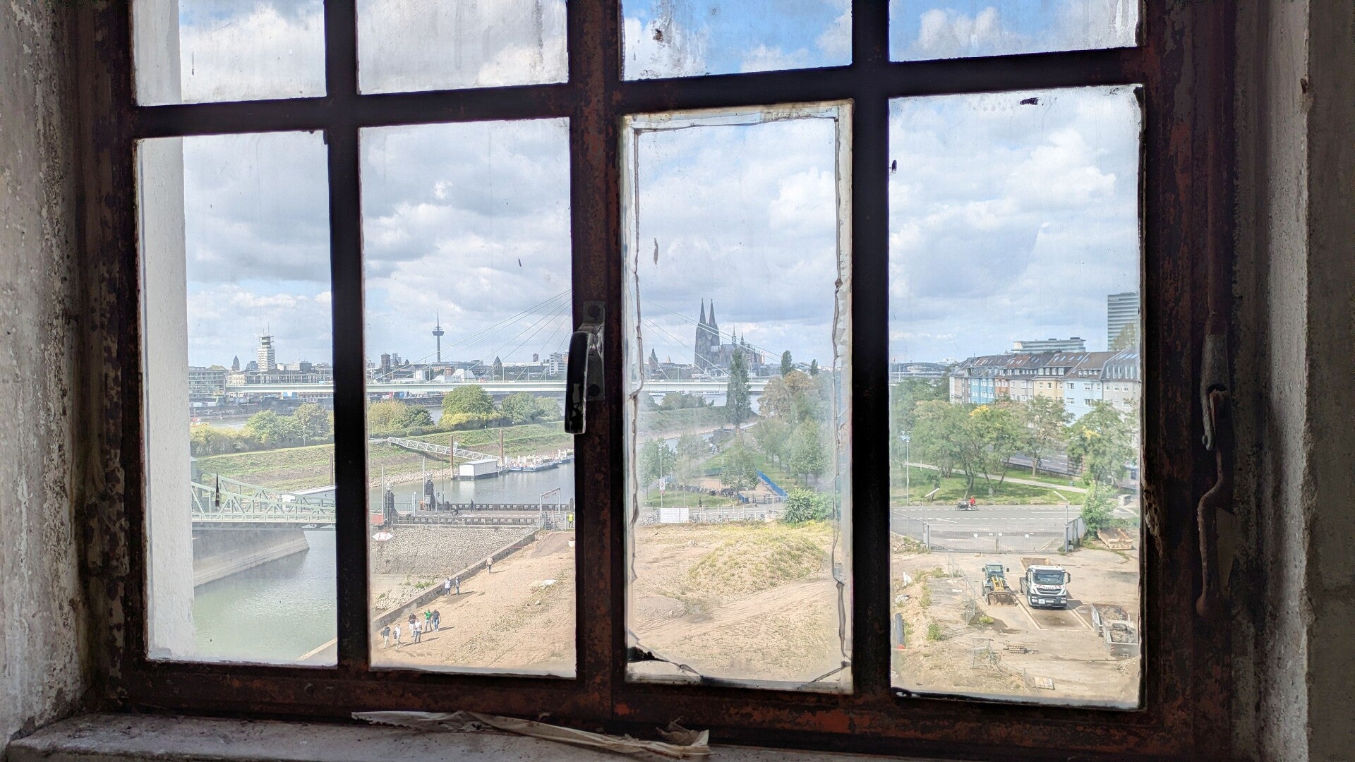 Ein Blick durch ein altes verwittertes Fenster auf den Dom und die Stadt in der Aurora Mühle in Köln Deutz.