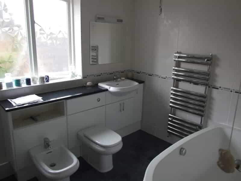 Full renovation of bathroom showing set of base units with bidet toilet, toilet, vanity basin,chrome towel rail, bath and fully tiled walls. Swanland.