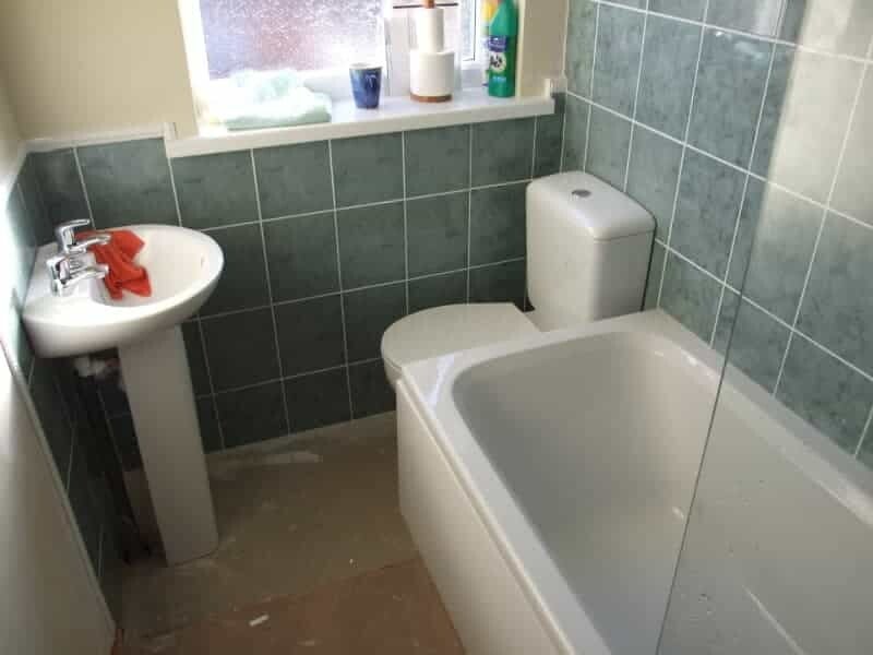 Completed bathroom showing toilet, basin, bath with over bath shower screen and tiled walls. Hull