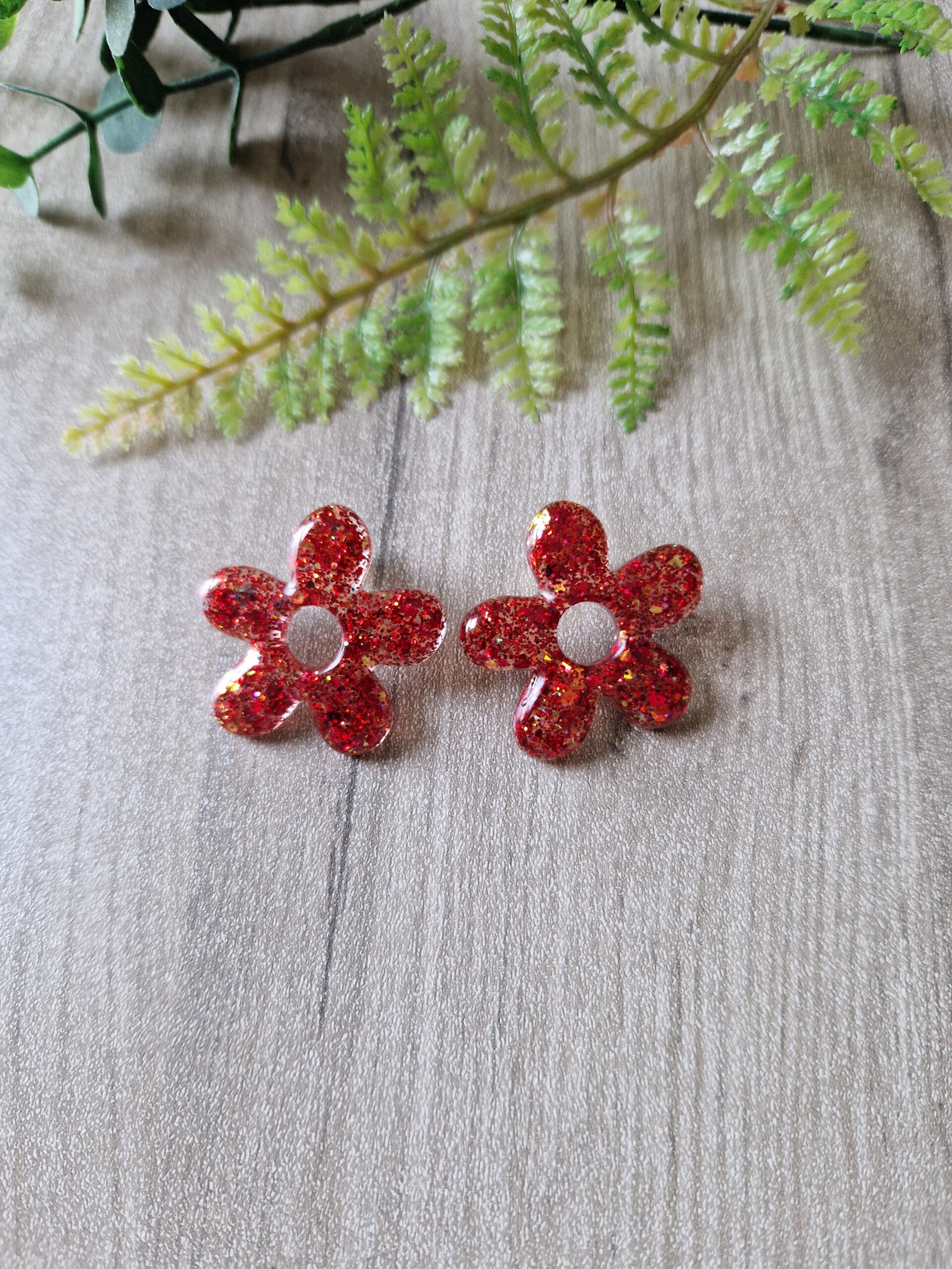 Boucles d'oreilles fleur en résine rouge pailletée.