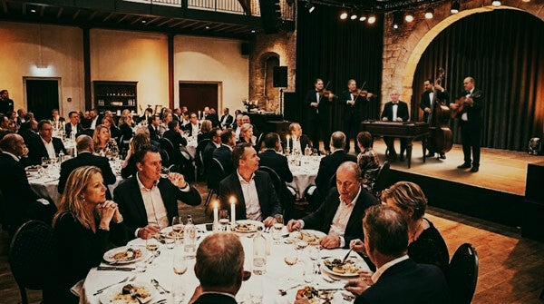 Een sfeervol galadiner in een elegante zaal met Varadi Ensemble op het podium in de achtergrond