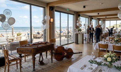 Beachclub voor het optreden van het Varadi Ensemble en uitzicht op zee tijdens 25-jarig jubileum.