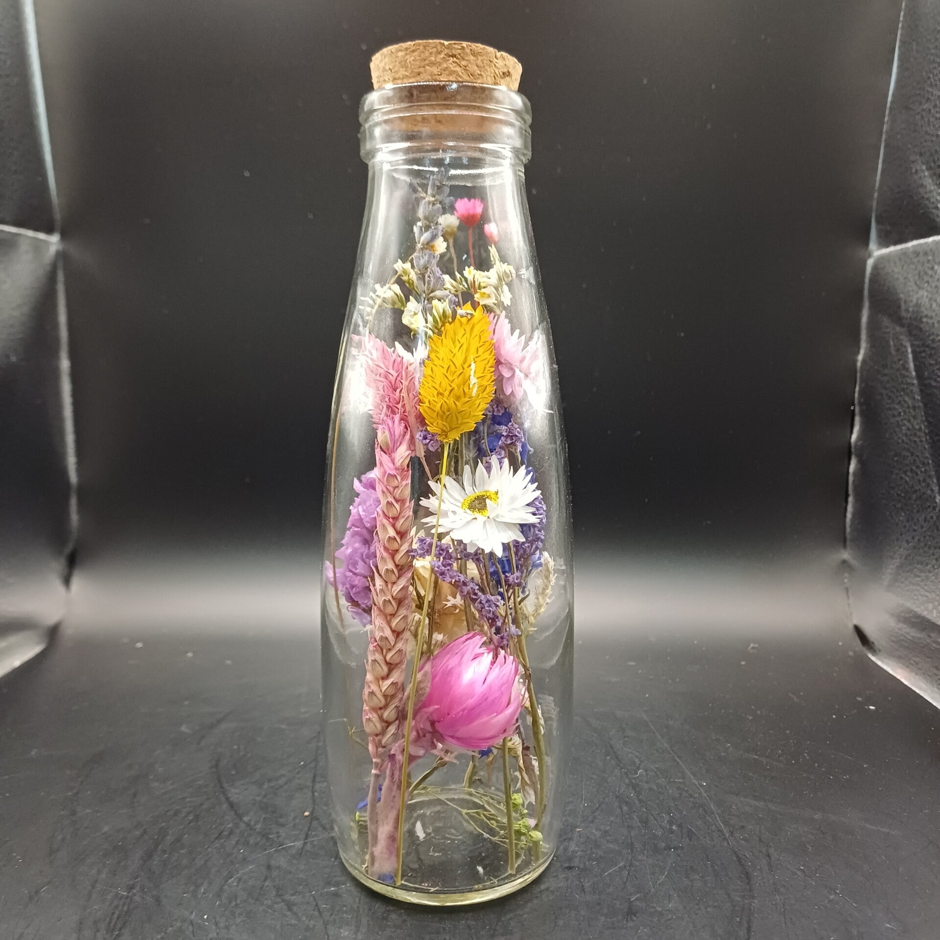 Glazen fles met fleurige droogbloemen en een kurk
