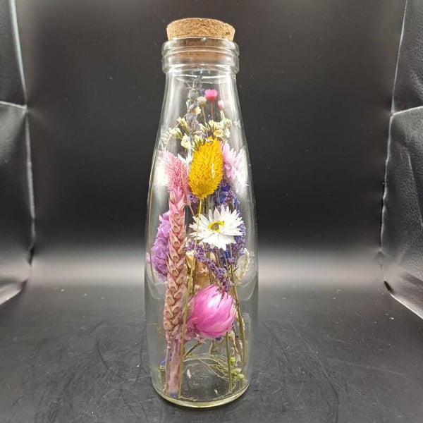 Glazen fles met fleurige droogbloemen en een kurk