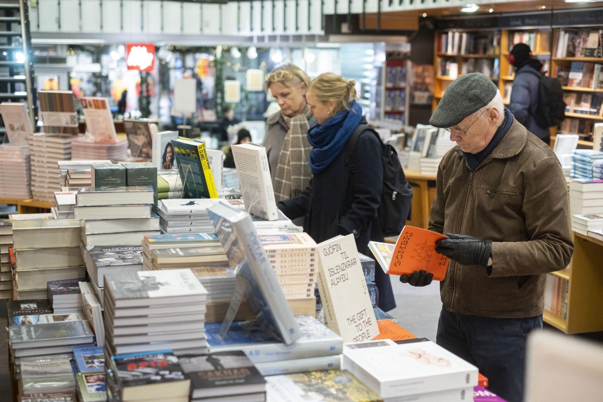 Customers browsing books in Iceland bookstore with stacks of new publications