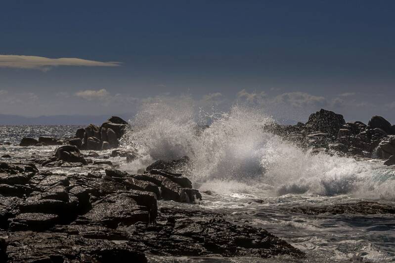 Mer agitée au large avec vagues argentées sous ciel sombre.