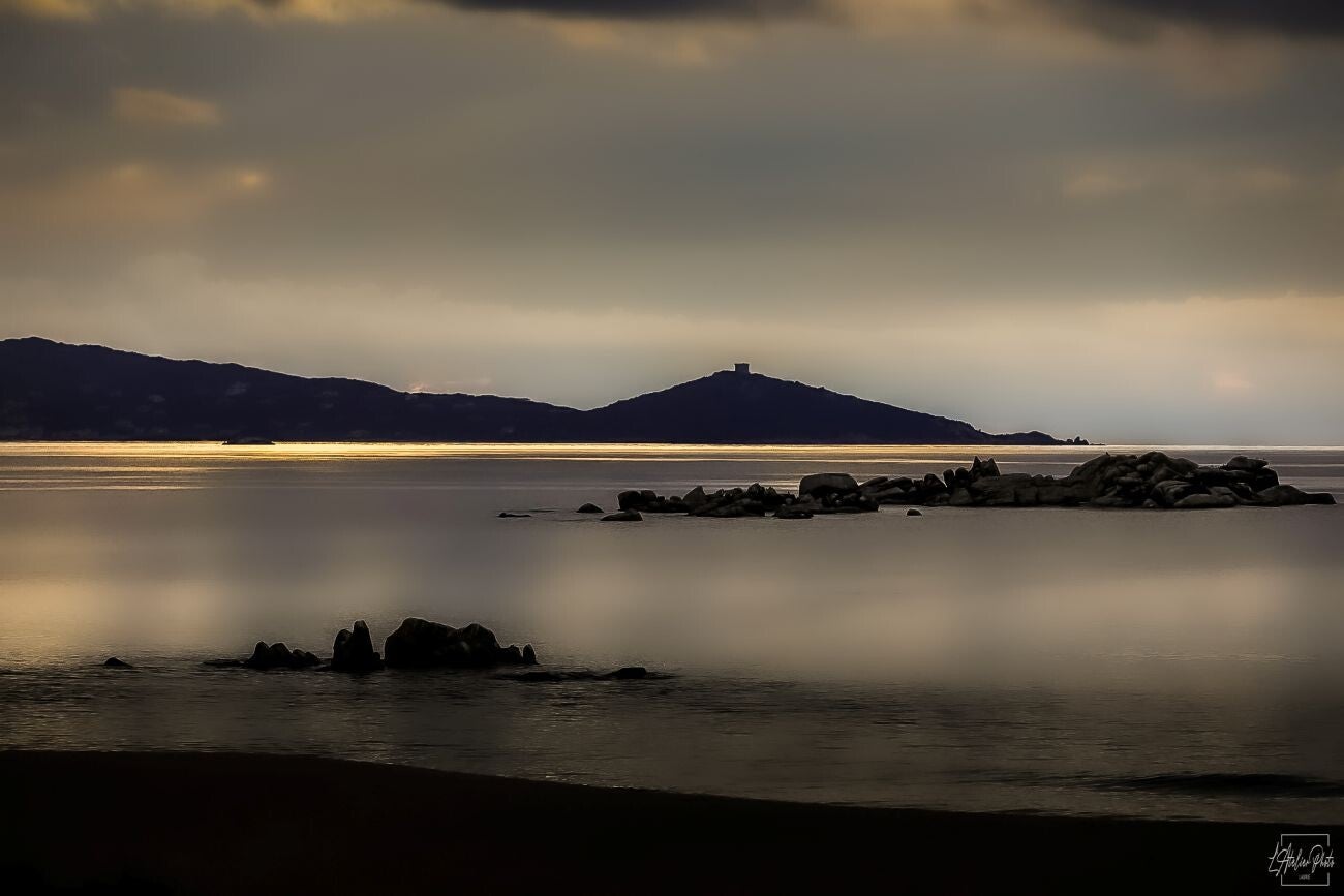Reflet doré sur une baie au crépuscule avec ligne de lumière sur la mer.