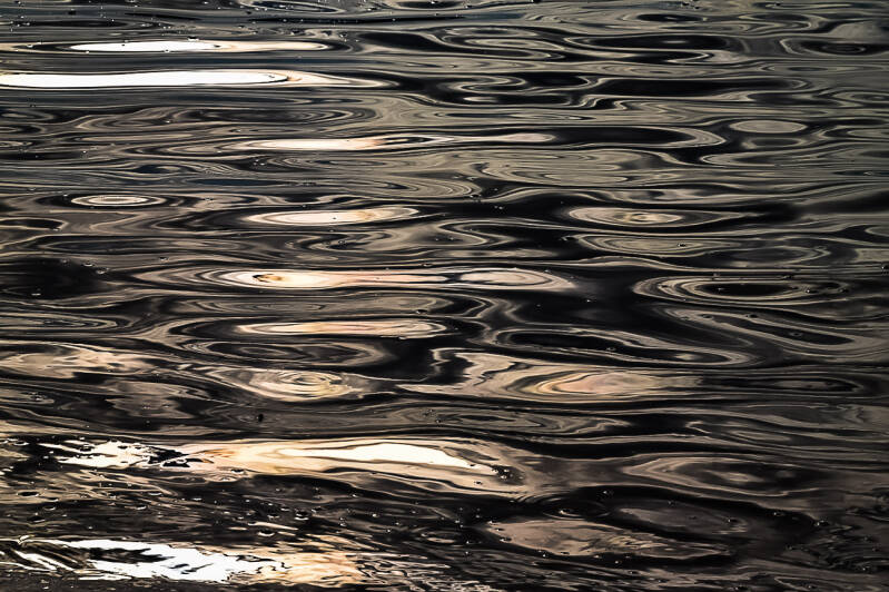 Reflets abstraits dorés à la surface de l’eau, textures liquides artistiques.