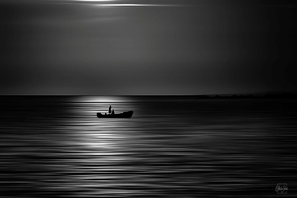 Pêcheur solitaire en noir et blanc sur une mer calme