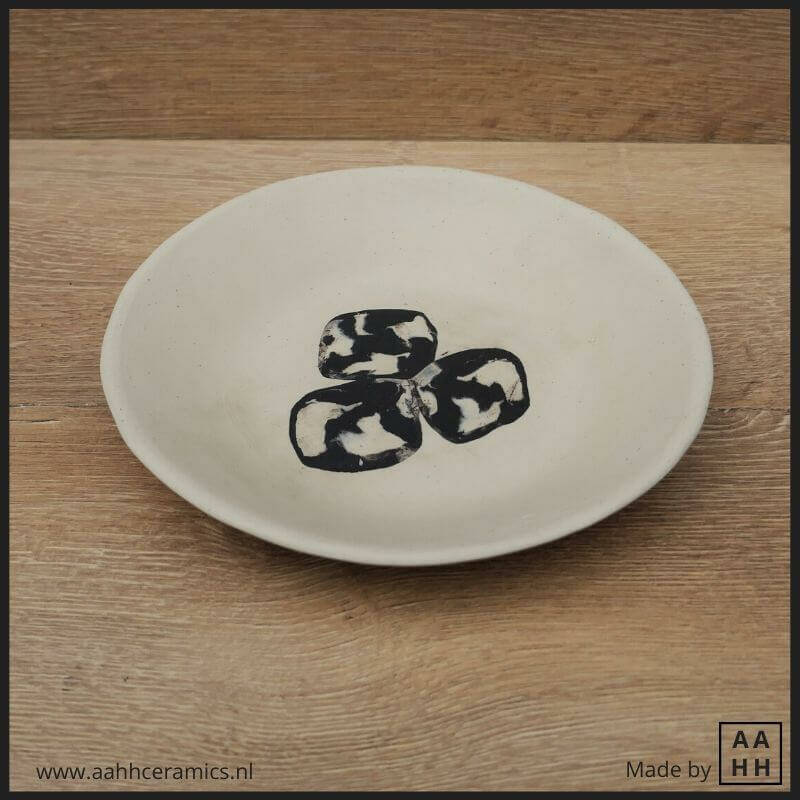 wit bordje met daarin uitgerold zwart-witte kleiplakjes