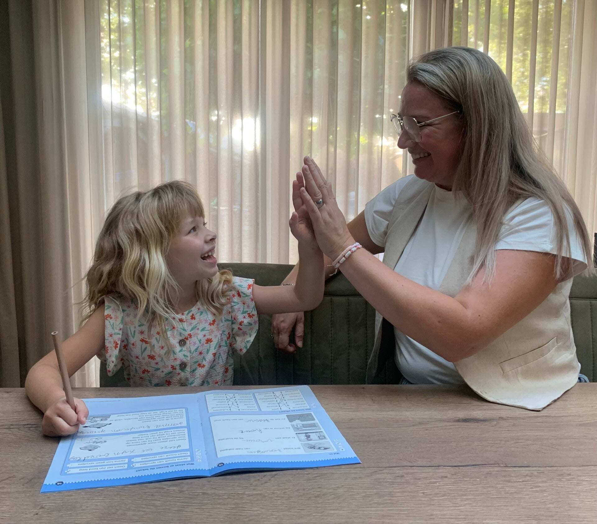 Dit is Anita Oerlemans die aan het werk is met een blij kind. Geven elkaar een  hi five omdat het gelukt is