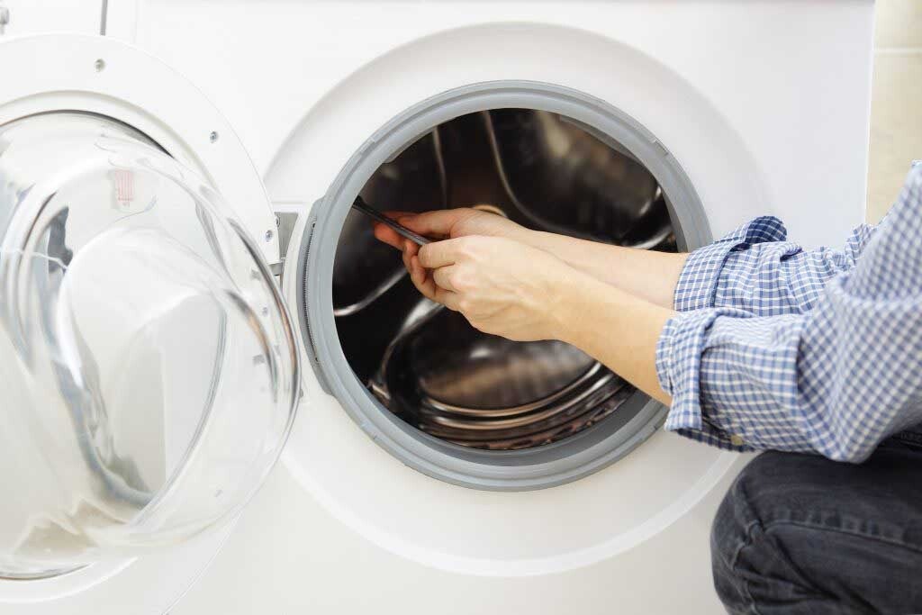 Appliance technician repairing clothes dryer 