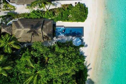 Villa's tussen palmen en wit strand op de Malediven