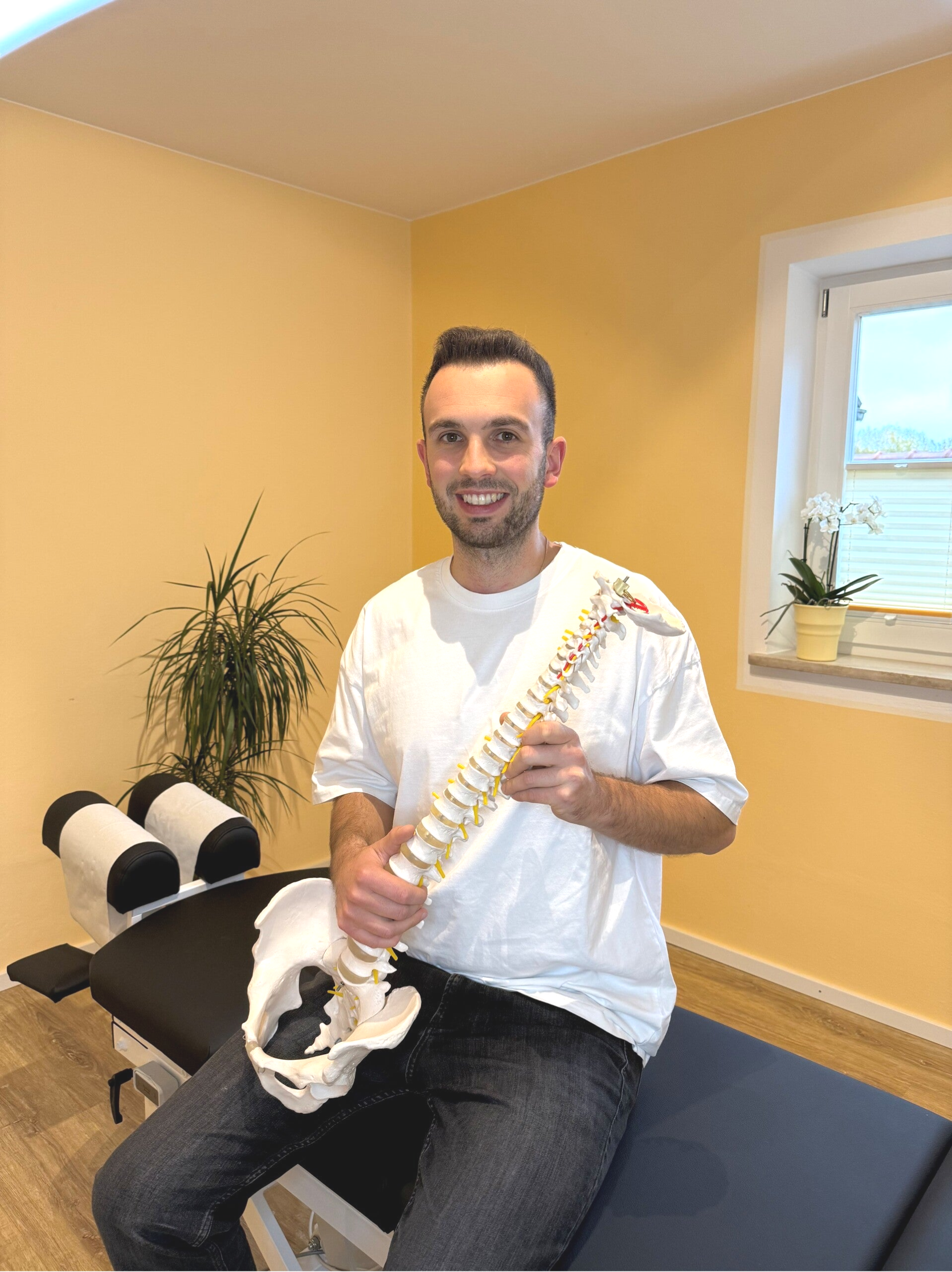 Chiropraktiker Johannes Hasch mit Wirbelsäule als Anschauungsobjekt