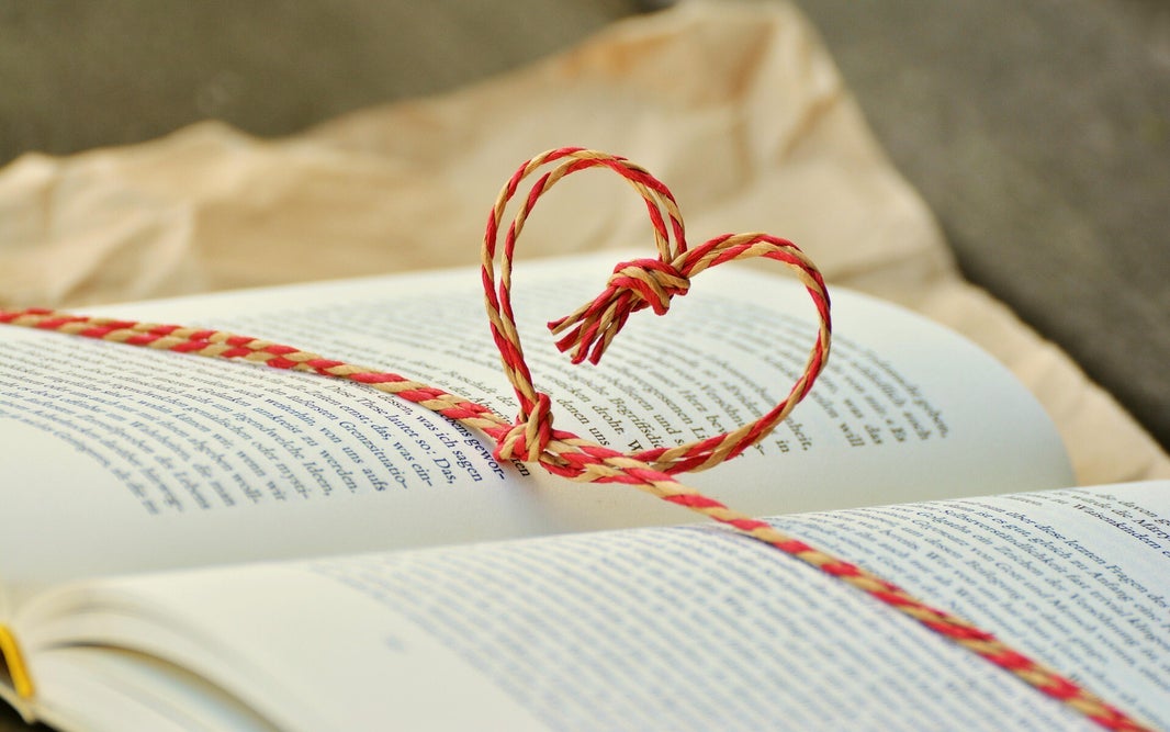 Libro abierto con un lazo rojo y amarillo en forma de corazón