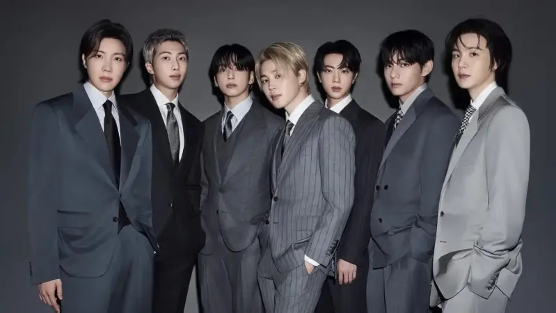 Miembros de BTS, vestidos con trajes grises oscuros.
