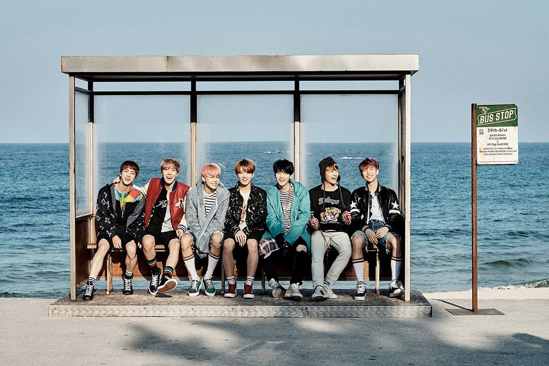 Foto del álbum YOU NEVER WALK ALONE, los 7 integrantes están en un Bus Stop junto a la playa