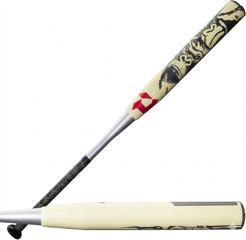 A two-view illustration of a beige and black baseball bat with a gorilla head graphic on the upper portion, a red logo, and a textured black handle, resting against another horizontal view of the bat on a white background.