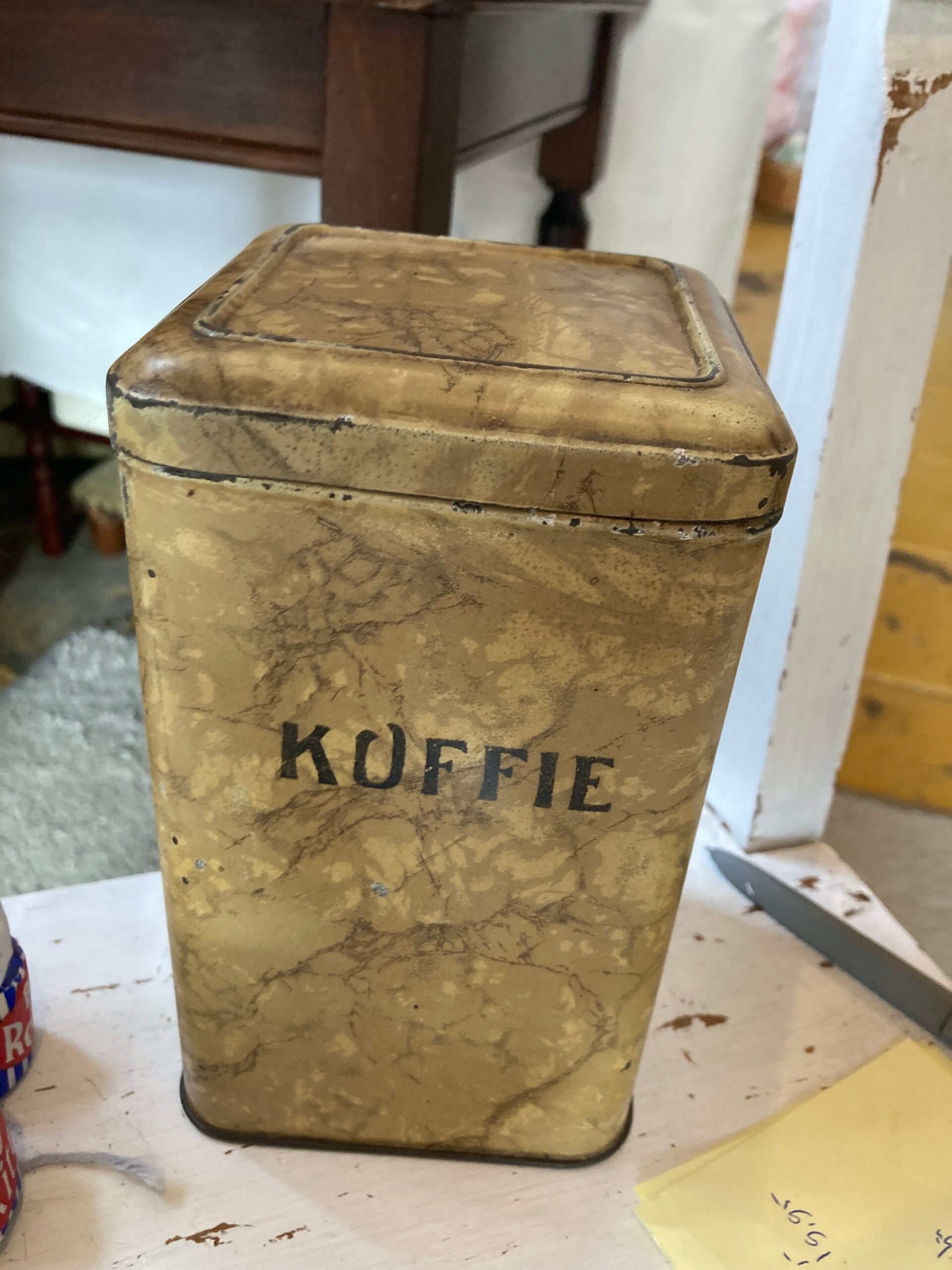 Oud koffieblikje met zwarte letters.