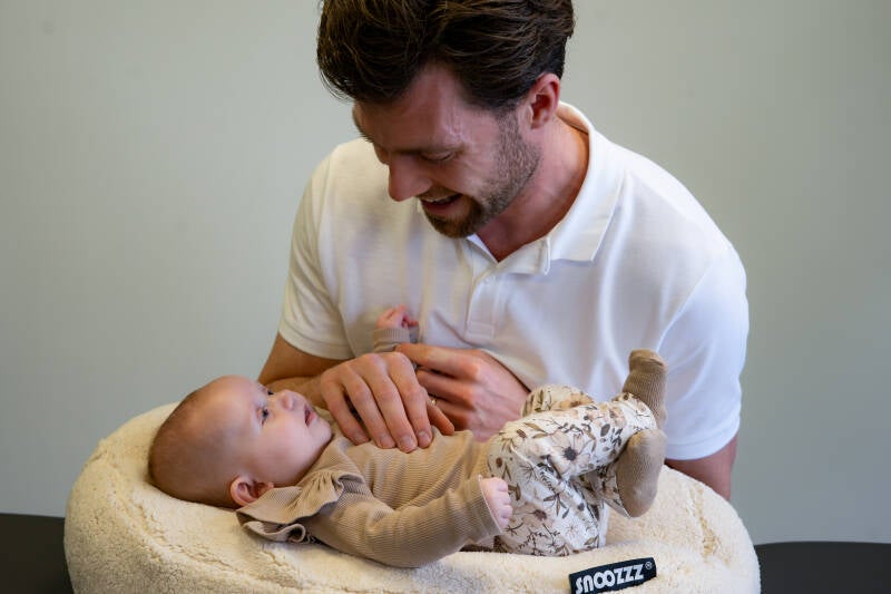 Een baby osteopaat onderzoekt zachtjes het lichaam van een baby tijdens een consult over een (te korte) tongriem.