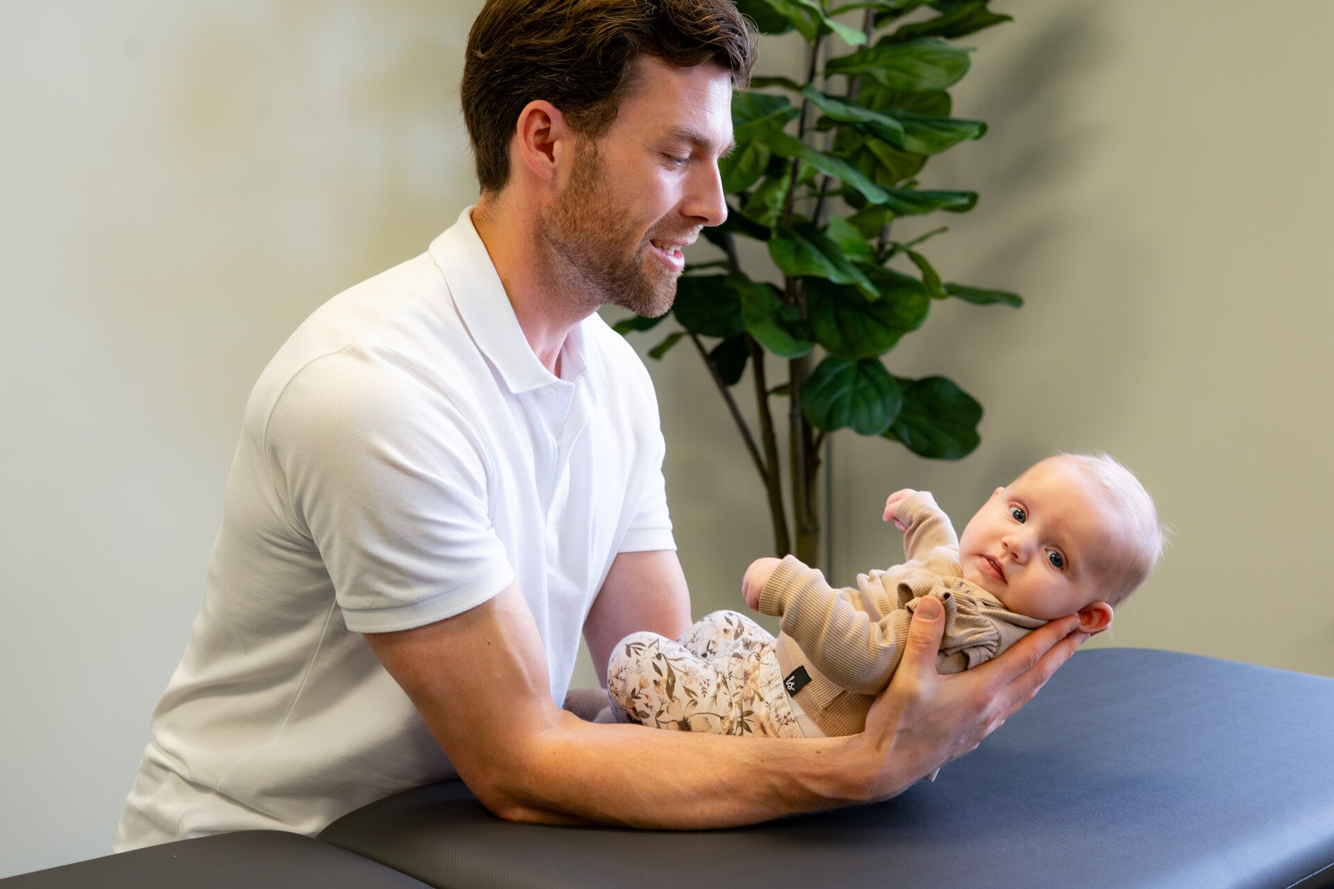 Een baby osteopaat behandelt op een zachte manier een baby met een voorkeurshouding op de behandelbank