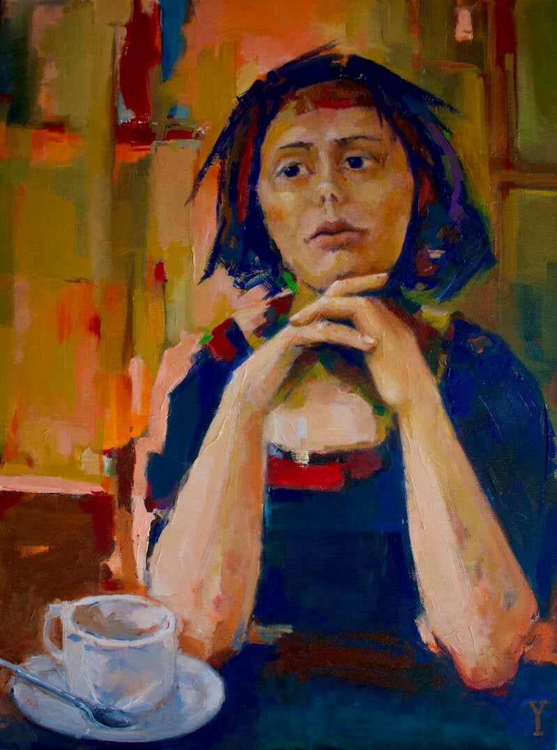 een jonge vrouw  zit in een kleurrijke ruimte achter een kop koffie. Even in zichzelf teruggetrokken. Onderdeel van de serie moments of reflexion 