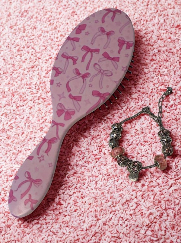 Pink brush with pink bows and charm bracelet.