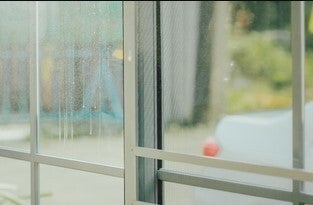 Experienced window fitter repairing failed seals and cracks on a  window frame to restore clarity and insulation.