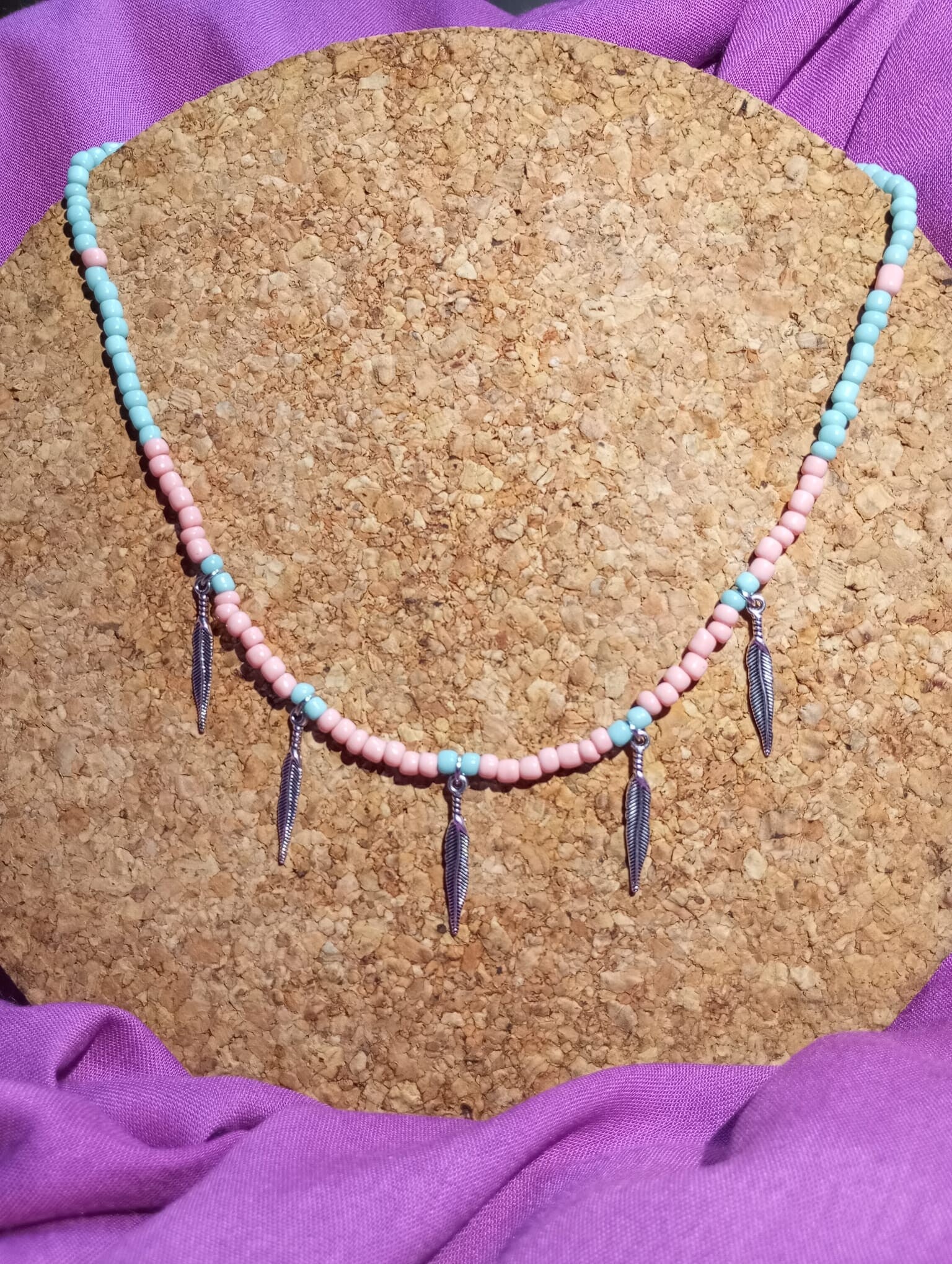 Collar rosa y celeste con plumas plateadas.