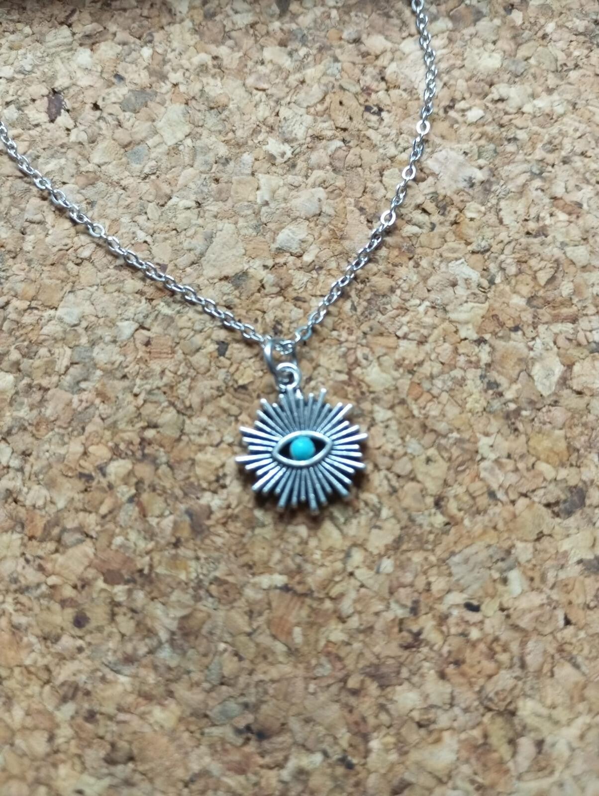 Cadena con colgante de sol y detalle turquesa.