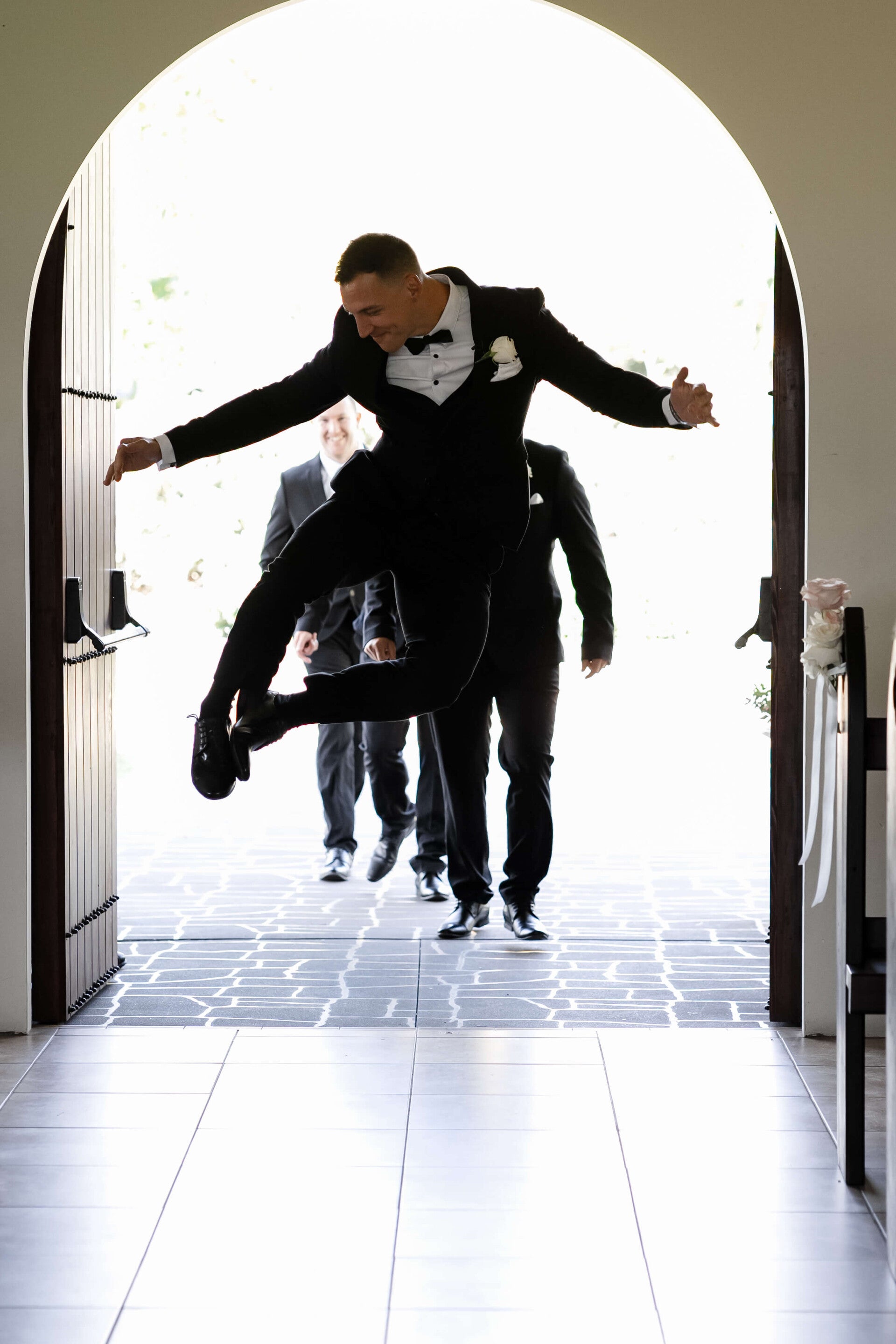 Groom jumping excitedly before wedding ceremony with groomsmen at Blue Mountains venue