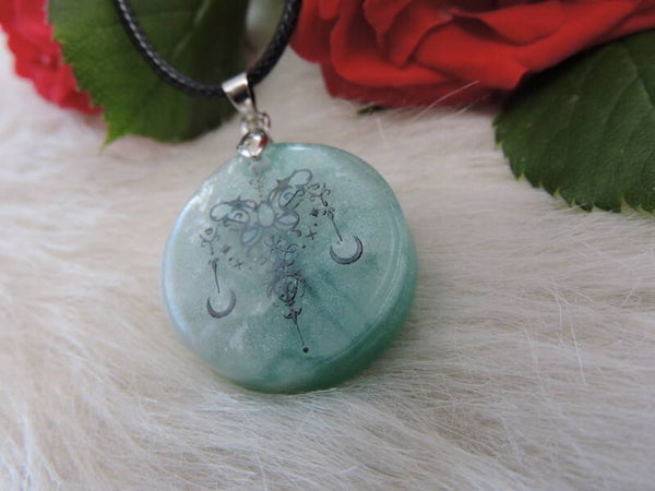 pendentif rond motif papillon attrape rêve sur fond vert lagon et blanc