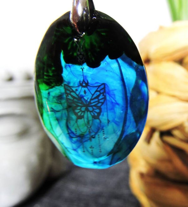 collier papillon sur fond  bleu et vert translucide