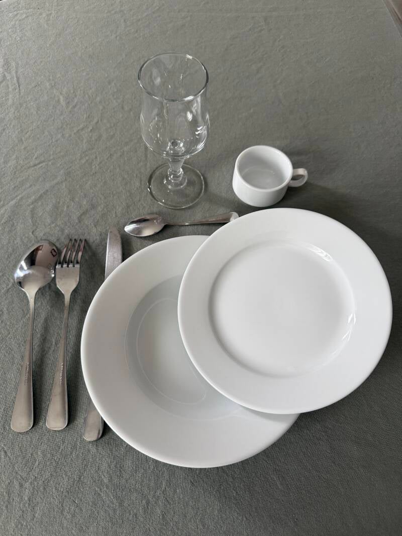 Kit essentiel dressé : verre à vin, assiette creuse, assiette à dessert, tasse, couverts. Location de vaisselle en Sarthe