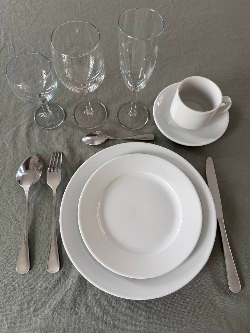 Kit élégance dressé : verre à eau, verre à vin, flûte, assiette 25 cm, assiette 19 cm, tasse et soucoupe, couverts. Location de vaisselle en Sarthe